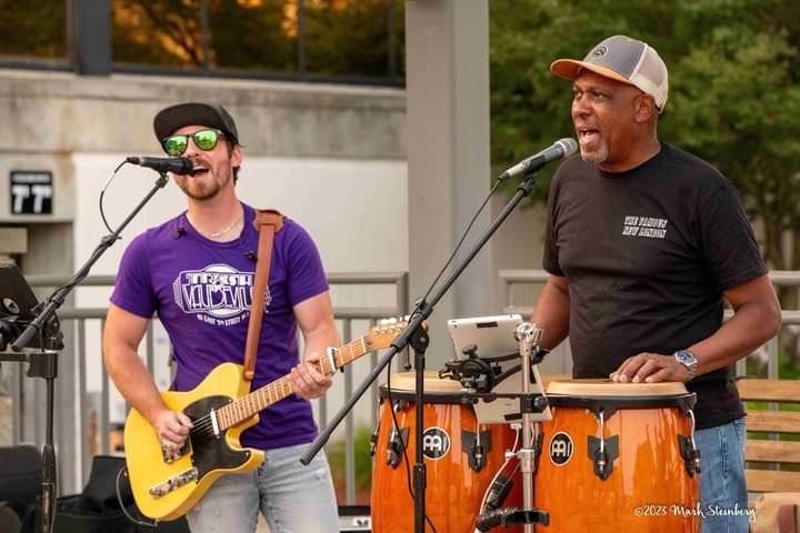 Andre on congas singing alongside a guitarist in a trio
